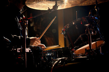 Drummer playing with drumsticks on a rock drum set.