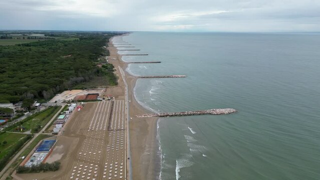 Smooth sea with beach and leaden rocks. Late spring, cloudy skies and rain to come. Italy, Veneto, shore of Eraclea