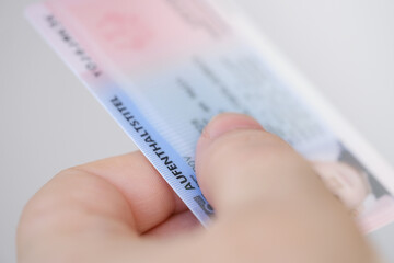 identity card, residence permit, personal document in female hand close-up with shallow depth of...