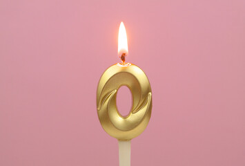 Golden birthday candle burning on pink background, number 0.