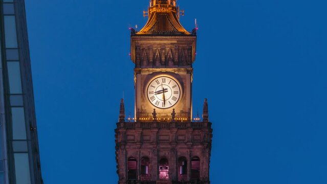 Day to night transition time lapse of illuminated large tower clock on the top of Palace of Culture and Science PKiN in Warsaw city Poland, zoom in effect. Arrow moving fast shows running time