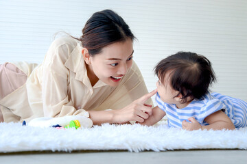 Happy toddle baby kid and mother sit on fluffy white rug floor in living room, little girl daughter and mom play with toys together, parent take care, look after infant child at home, love in family.