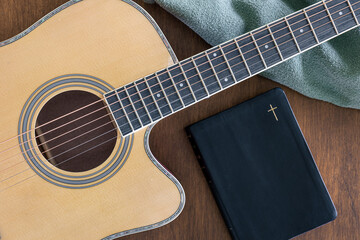 Guitar and bible book on wooden background, top view.
