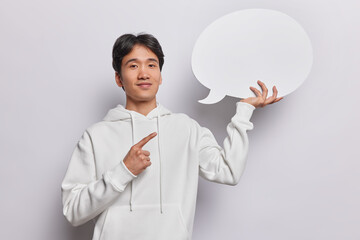 Smiling Japanese points at blank speech bubble suggests to write your idea here dressed in casual...
