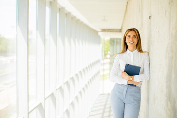 Young business woman holding with notebook in the office hallway