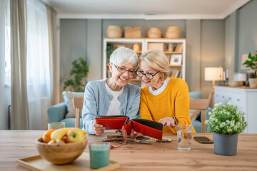 Senior mature women friends or sisters looking family photos album
