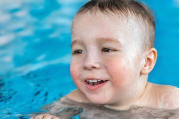 Fototapeta na wymiar close-up portrait of joyful baby swimming in the pool, children's day