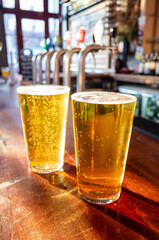 Close up of pint glass of lager on the bar of a traditional English pub in the UK