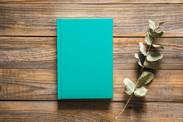 Closed green book on wooden background, top view.