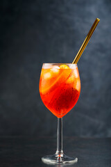 Aperol Spritz cocktail on dark background. Cocktail Aperol Spritz with oranges and ice in glass with eco-friendly glass straw