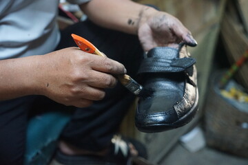 Temanggung, Indonesia - May 10 2023 : An Asian shoe sole repairman is polishing his wares