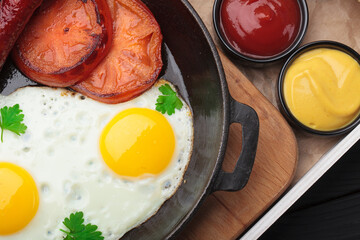 Fried eggs with beautiful yolks and sausages in a cast-iron skillet