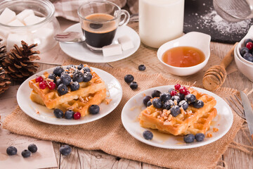 Waffles with red currant and blueberries on white dish. - 602332297