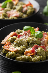 Italian potato gnocchi with green pesto sauce, bacon and parmesan cheese. Healthy food