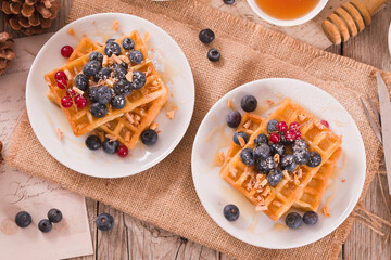 Waffles with red currant and blueberries on white dish. - 602332474
