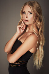 Naklejka premium Beauty, face and portrait of a woman in studio with makeup, cosmetics and long hair. Headshot of a female aesthetic model with a natural glow, sexy style and seductive pose on a grey background
