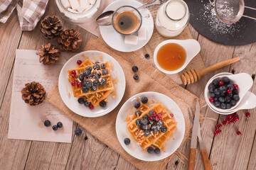 Waffles with red currant and blueberries on white dish. - 602332628