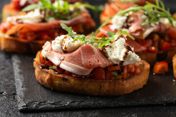 Parma ham and tomato bruschetta served on black slate with mozzarella, wild rocket leaves and balsamic vinegar