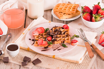 Waffles with strawberries and chocolate cream.