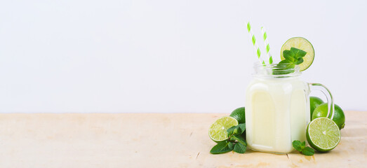 Brazilian Lemonade, Refreshing Creamy Lemonade or Limeade with Lime Slices and Mint on Bright Beige Background