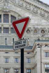 Paris, France - 16 April 2023:  Road yield sign with the building of the Paris Opera Garnier in the background