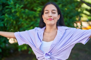 Young beautiful hispanic woman breathing with closed eyes at park