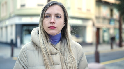 Young blonde woman standing with relaxed expression at street