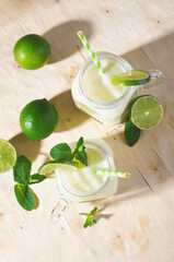 Brazilian Lemonade, Refreshing Creamy Lemonade or Limeade with Lime Slices and Mint on Bright Beige Background