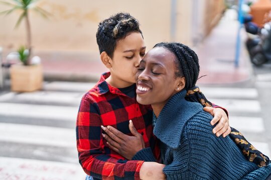 African american mother and son smiling confident hugging each other and kissing at street