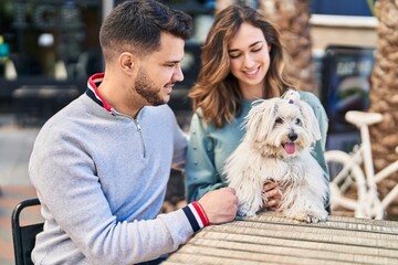 Man and woman holding dog hugging each other at coffee shop terrace