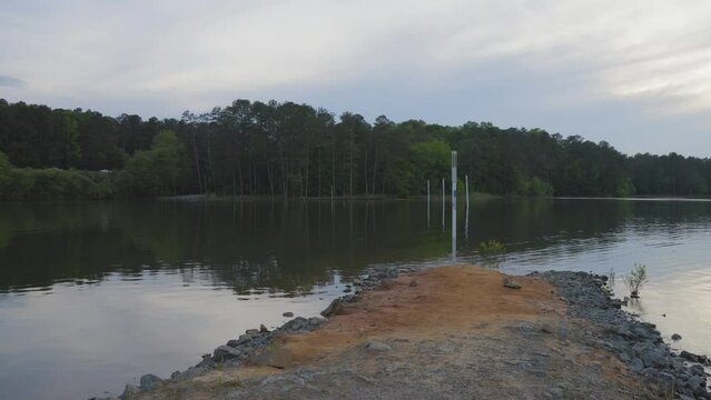 footage of a gorgeous spring landscape at Proctor Landing Park at sunset with rippling water surrounded by lush green trees and plants and a pergola with benches at Lake Acworth in Acworth Georgia USA