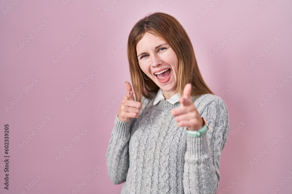 Poster beautiful woman standing over pink background pointing fingers to camera with happy and funny face. 