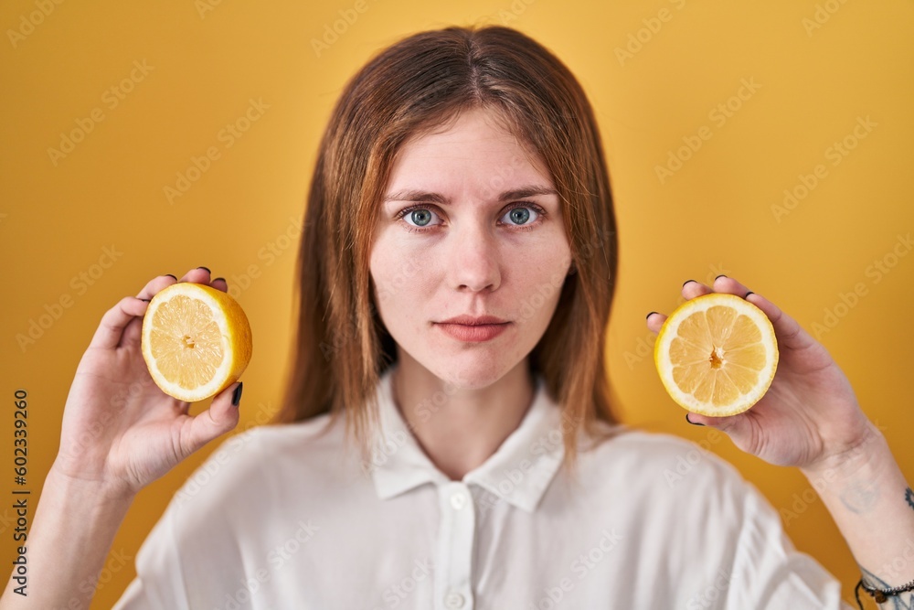 Canvas Prints Beautiful woman holding lemons relaxed with serious expression on face. simple and natural looking at the camera.