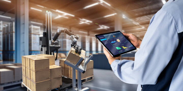 Smart Warehouse,Inventory management system concept.Manager using digital tablet,showing warehouse software management dashboard on blurred warehouse as background