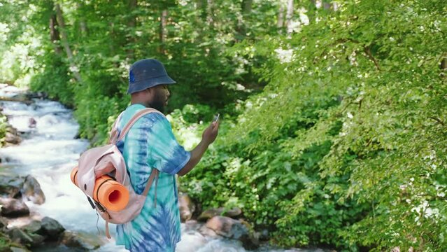 african man tourist photographing by smartphone beautiful nature of forest in summer day during hike