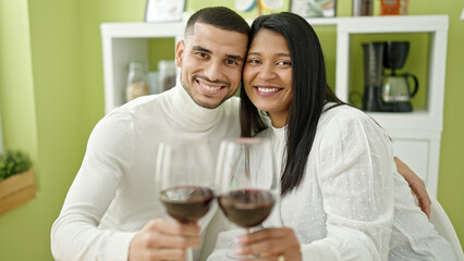 Man and woman couple hugging each other toasting with glass of wine at home