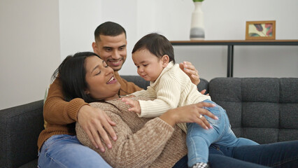 Couple and son hugging each other sitting on sofa at home