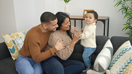 Couple and son hugging each other sitting on sofa at home