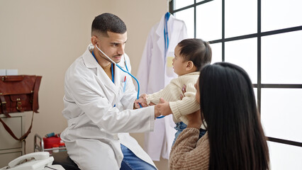 Obraz premium Couple and son examining baby with stethoscope at clinic