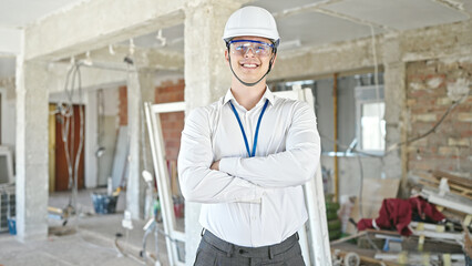 Young hispanic man architect smiling confident standing with arms crossed gesture at construction site