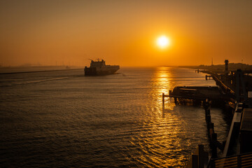 ship sails into glorious sunset on waterline of Dutch port harbour dock in Hook of Holland...