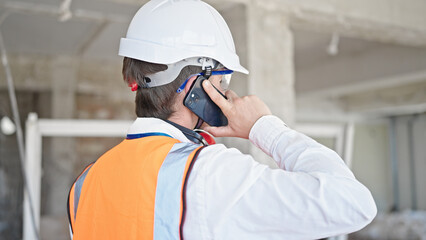 Young caucasian man architect talking on smartphone at construction site