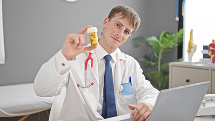 Young caucasian man doctor using laptop prescribing pills at clinic