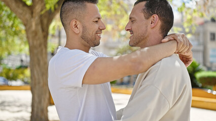 Fototapeta premium Two men couple smiling confident hugging each other at park