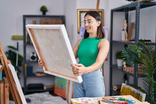 Young hispanic woman artist smiling confident holding draw at art studio