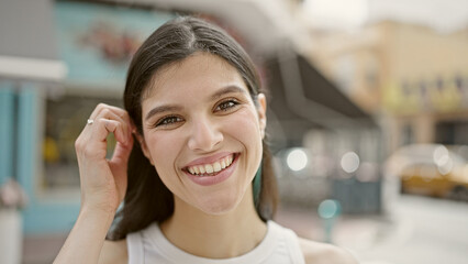 Young beautiful hispanic woman smiling confident standing at coffee shop terrace