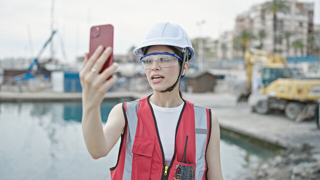 Young beautiful hispanic woman builder having video call at seaside