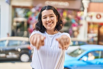 Young woman smiling confident pointing with fingers at street