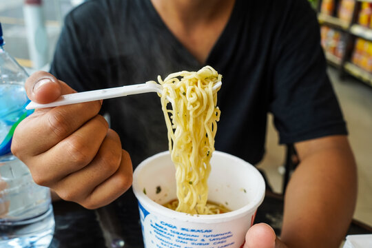 instant noodles, noodle soup in a cup, boys hand feeding ready to eat noodles