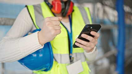 Young blonde woman architect using smartphone with winner expression at street